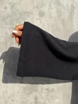 Polerón negro de calce holgado con cuello alto y mangas amplias, confeccionado en tela suave y abrigada.