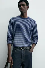 Camiseta de manga larga con cuello redondo y efecto lavado. Presenta un patrón de rayas horizontales finas en azul marino y blanco/beige.