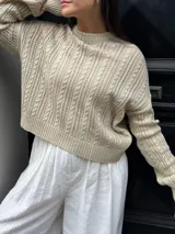 Sweater color crema tejido con diseño en ochos y cuello redondo.