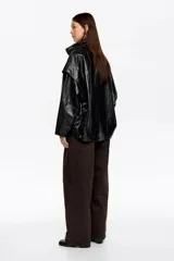 Cazadora de corte oversize confeccionada en piel, con cremallera metálica frontal oculta, cuello subido y manga larga con forma. Cuenta con bolsillos tipo alforja.
