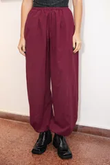 Pantalón tipo babucha de silueta relajada, color bordo, con cintura elástica ajustable mediante cordón y elásticos en los tobillos que generan un efecto abuchonado. Confeccionado en tela suave con acabado tipo piel de durazno.