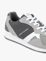 Zapatillas tipo runner de Tommy Hilfiger en tonos gris y gris oscuro, con detalles en blanco. Confeccionadas en una mezcla de cuero y textil, cuentan con pasadores blancos, suela de goma blanca y diseño lateral característico de la marca.