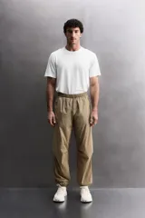 Pantalón jogger de corte regular confeccionado en tejido técnico ligero, con cintura elástica, bolsillos laterales con cierre y puños elásticos en los tobillos.