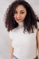 Top sin mangas, cuello tortuga, color blanco con acabado brillante o metálico. Tejido acanalado y ajustado al cuerpo.