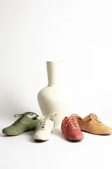 Zapatillas bajas color crema con cordones y suela marrón.