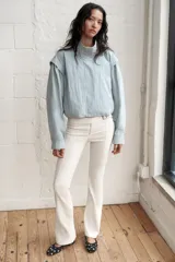 Chaqueta corta de cuello subido con manga larga, cierre frontal con cremallera y botones a presión ocultos. Presenta bolsillos delanteros y puños con pliegues.