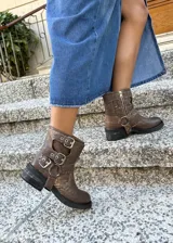 Botas cortas de cuero vacuno color marrón con efecto gastado, cierre lateral y hebillas decorativas.