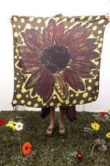 Pañuelo cuadrado de poliéster con estampado de lunares amarillos sobre fondo marrón y una gran flor bordó en el centro.