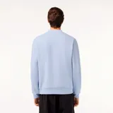 Buzo Lacoste celeste de corte clásico, confeccionado en algodón orgánico y poliéster reciclado. Presenta cuello redondo con inscripción de la marca y logo de cocodrilo en el pecho.