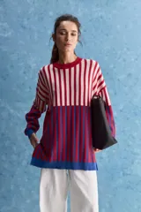 Sweater de tejido jacquard con diseño de rayas verticales en tonos rojo, blanco y azul. Presenta cuello redondo, hombros caídos y puños en contraste de color azul.