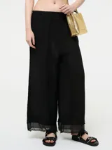 Pantalón negro de lino de corte ancho, con cintura elástica, lazo ajustable y bajo desflecado.