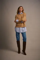 Sweater tejido color marrón claro, de escote redondo y calce holgado. Tiene hombros caídos, mangas largas y puños tejidos.