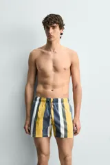 Bañador de hombre con estampado de rayas verticales anchas en tonos amarillo mostaza, azul oscuro desgastado, blanco y gris. Posee cintura elástica con cordón ajustable y bolsillos laterales.
