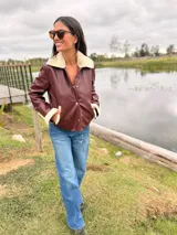 Campera tipo slouchy jacket de cuero de oveja color bordó, con cuello y detalles en puños de piel sintética color crema. Presenta cierre frontal con botones a presión y bolsillos laterales.