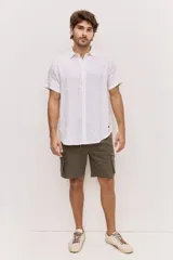 Camisa de manga corta en color blanco, con cuello clásico y cierre frontal de botones al tono. Presenta un diseño versátil de corte regular y textura liviana, ideal para looks frescos.