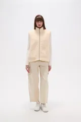 Chaleco sin mangas de textura peluche (teddy) color crema, con cuello alto y cierre frontal de cremallera.