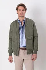 Campera bomber verde militar de nylon, con cuello y puños de algodón, cierre frontal y bolsillos con solapa y botón.