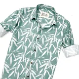 Camisa de manga larga verde con estampado de hojas blancas, cuello clásico y cierre con botones.