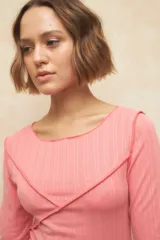 Remera negra de manga tres cuartos, escote redondo y detalle de costuras superpuestas de forma asimétrica.