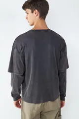 Camiseta de manga larga con diseño de doble capa en las mangas, cuello redondo y acabado efecto lavado desgastado en color negro.