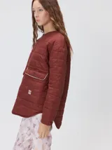 Campera reversible capitoneada con cierre frontal. Un lado es de color negro y el otro es de color beige, ambos con diseño acolchado. Cuenta con cuello redondo, mangas largas y bolsillos laterales.