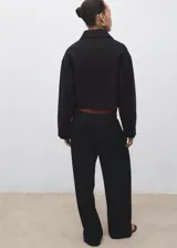 Chaqueta corta de corte recto con cuello camisero, cierre frontal de botones y dos bolsillos de parche laterales. Presenta mangas largas y forro interior.