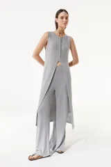 Pantalón gris de tejido de punto confeccionado en lurex. De tiro alto con elástico en la cintura, la pierna se ensancha en el ruedo y cuenta con tajos en los laterales.