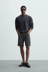 Bermuda de denim de algodón con elasticidad, color negro lavado. Modelo de tiro medio con corte regular fit, cinco bolsillos y cierre frontal con cremallera y botón.