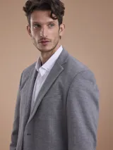 Blazer formal color negro, confeccionado en tela texturada, con solapas clásicas, cierre de dos botones frontales y bolsillos con solapa.