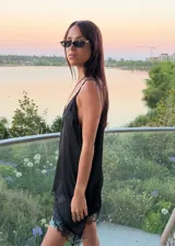 Blusa tipo lencera de satén color crema con escote en V y ruedo asimétrico, ambos decorados con encaje negro. Presenta breteles finos ajustables.