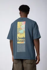 Remera de corte oversize color beige, confeccionada en algodón grueso. Presenta una estampa frontal pequeña con diseño artístico abstracto en tonos azules y amarillos.