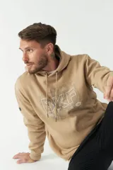 Buzo canguro color beige de felpa con capucha ajustable con cordones y bolsillo canguro. Estampado frontal con letras y mapa.