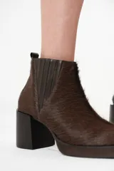 Botas Chelsea de cuero con pelo color marrón oscuro, con elásticos laterales y cierre interno. Taco bloque de madera y plataforma delantera.