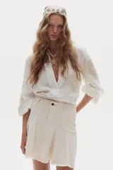 Minifalda blanca de denim con diseño evasé, godets que aportan movimiento y ruedo desflecado.