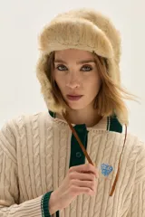 Sweater de punto con diseño de ochos en color crudo, con cuello polo y tapeta de botones en contraste verde. Presenta bordado en el pecho, puños y ruedo acanalados con detalles de rayas en verde.