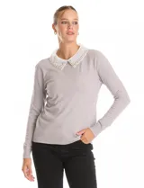 Buzo de punto fino color gris, con cuello camisero de gasa integrado decorado con apliques de perlas y brillos. Presenta mangas largas y puños acanalados.