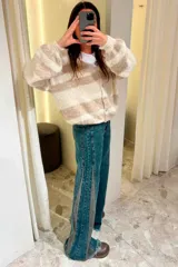 Pantalón de jean azul oscuro de pierna ancha y tiro medio, con paneles laterales en contraste de color marrón. Presenta costuras pespunteadas en tono tostado y terminación desmechada en el bajo.