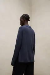 Sweater de punto color beige, de corte relajado y largo a la cadera, con cuello tipo polo, escote en V, mangas largas y aberturas laterales.