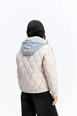 Campera puffer negra con diseño matelaseado en rombos, capucha integrada, cierre frontal y puños elásticos.