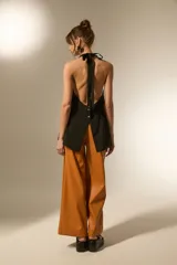 Chaleco largo negro, con escote halter y abertura frontal con botones joya. Corte entallado en la parte superior y ligeramente acampanado en el bajo.