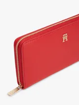 Billetera Tommy Hilfiger de color rojo con acabado granulado y cierre integral de cremallera. Presenta dos compartimentos principales, múltiples ranuras para tarjetas, un bolsillo interior con cremallera y el monograma TH metálico en la parte delantera.