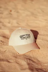 Gorra color crudo con logo bordado en negro en el frente.