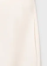 Pantalón tiro medio color crudo de diseño recto y largo, con cintura de goma elástica, sin cierre y dos bolsillos laterales.