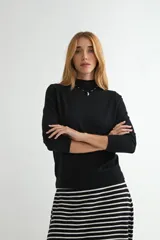 Polera de punto color beige, con cuello alto y mangas largas, de diseño básico y ajuste clásico.