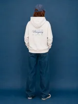 Buzo con capucha color off-white, de corte holgado, con bolsillo frontal tipo canguro y estampado pequeño en el pecho con la frase 'Tierra de Campeones' y cuatro estrellas en color azul.