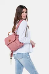 Mochila de lona estilo vintage con solapa frontal, bolsillos laterales y correas ajustables. Presenta detalles en cuero sintético y un parche decorativo en la parte superior.