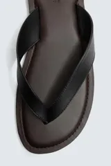 Sandalia tipo chancleta negra con suela plana marrón y dos tiras en el empeine.