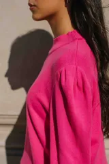 Sweater de hilo color fucsia, con cuello redondo y hombros abullonados.