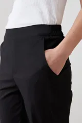 Pantalón de corte recto en color beige, con cintura media y cierre frontal oculto. Presenta un diseño limpio y minimalista con bolsillos laterales.