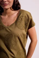 Remera de algodón color blanco con cuello en V y mangas cortas. Presenta un diseño con flores bordadas en relieve y detalles calados en el tejido.